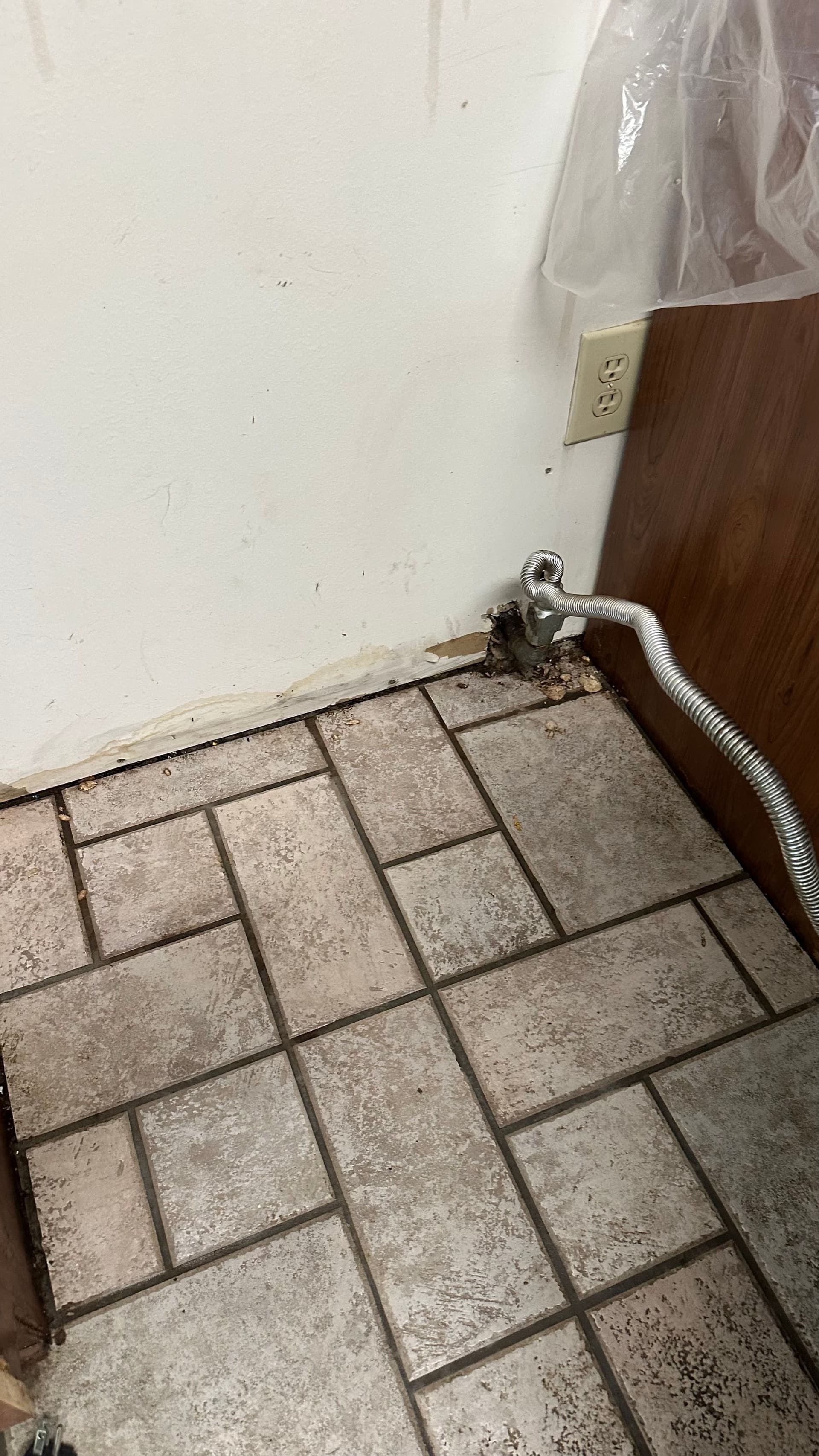 A tiled floor with dust along the baseboard before cleaning